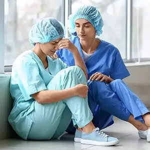 Two medical professionals in scrubs mourning an unexpected loss.