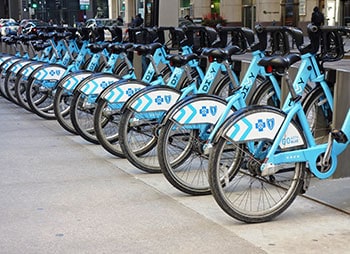 Row of blue bikes parked on the sidewalk - Sharks at Law