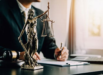 A lawyer in an office with a statue of Lady Justice - Sharks at Law