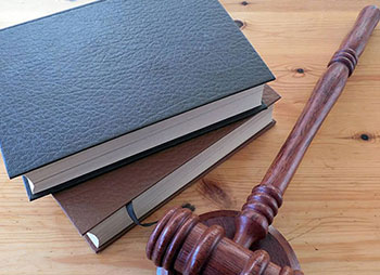 A table with books and a wooden gavel placed on it - Sharks at Law