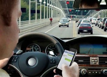 A man using his cell phone while driving a car - Sharks at Law