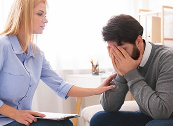 A supportive woman comforts a distressed man, representing emotional toll after an injury