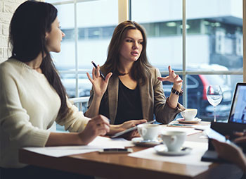 Two women talking in a legal consultation setting, Hiring an Attorney for Injury Recovery