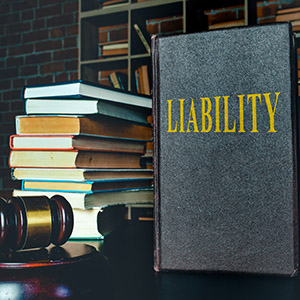 Book labeled LIABILITY on a desk with a gavel and stacked legal books, discussing injury claims against friends family in Cook County, IL.